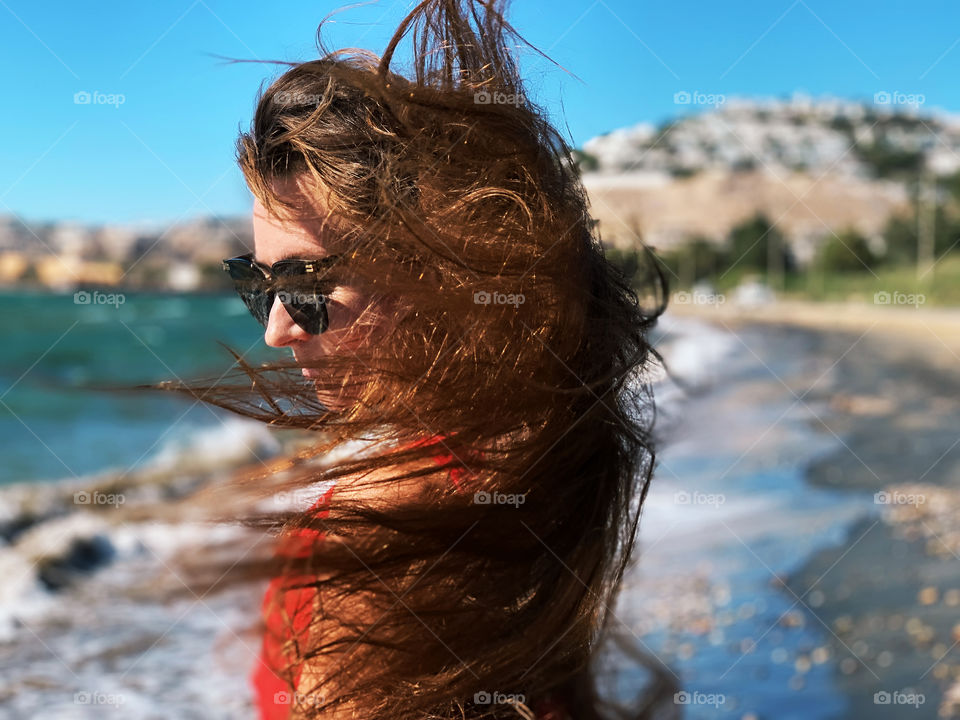 Wind in long hair of a young woman at the seaside 