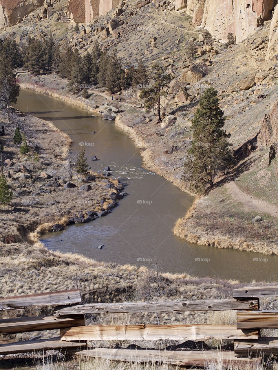 The smooth flowing waters of the Crooked River wind the steep canyons at Smith Rock State Park with both juniper and ponderosa pine trees on its banks on a stormy winter day in Central Oregon.