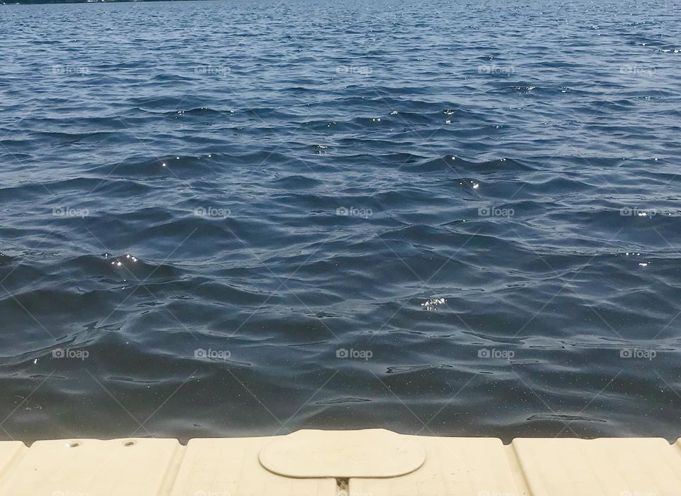 Lake Daze; Ripples along a lake bouncing off a pier 