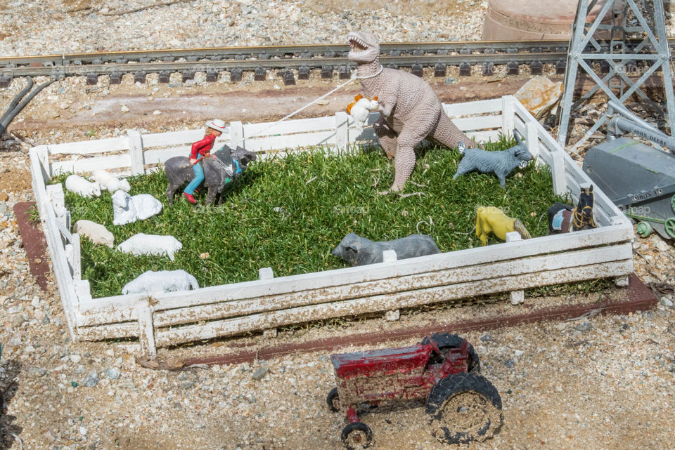 Diorama of cowgirl lassoing a T-Rex while it's trying to steal a duck. 