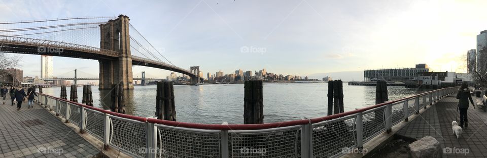 Brooklyn Bridge over the glistening water, connecting Brooklyn to the bustle of business at Wall Street