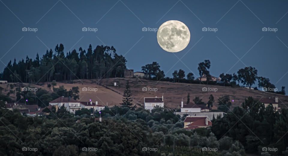 A full harvest moon, watches over a rural village 