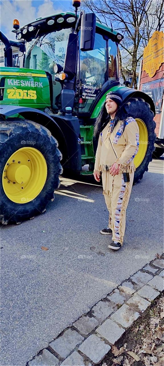 „Winnetou“ stands next to a „Wild West“ float in full regalia in his embroidered suit with fringes greeting the admiring public in the carnival parade in „Bad Füssing“, „Bavaria“, Germany on „Mardi Gras“ or „Fat Tuesday“. 2024. Hypnotic Productions