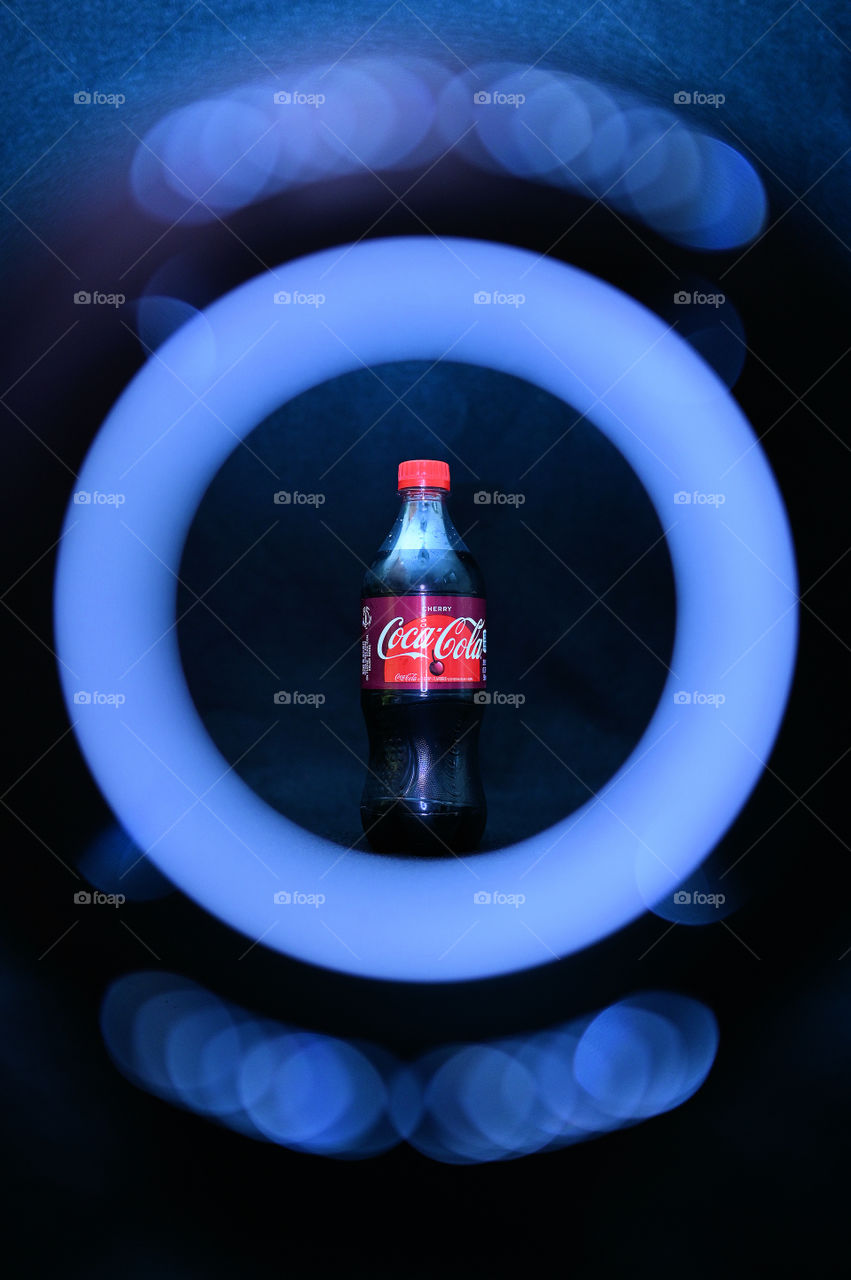 Close up shot of two Coca Cola with black background with the mists at the studio, with light rings. 
