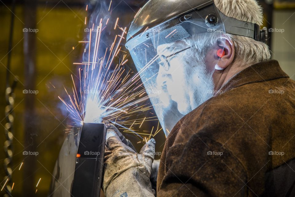 This welder is building a frame by welding bar steel together using fixtures to produce a ROPS frame for a heavy equipment Cab. 