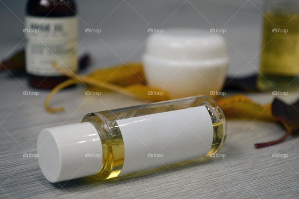 Jars with cream, shampoo and cosmetics on a background with autumn leaves