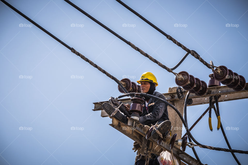 Electrician working on the electricity pole to replace the electrical insulator