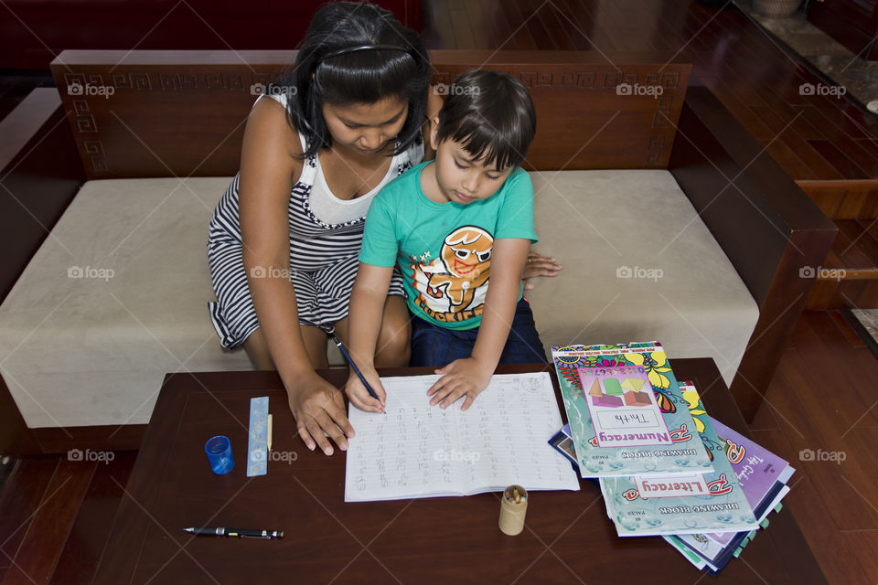 Asian mother helping her son with homework