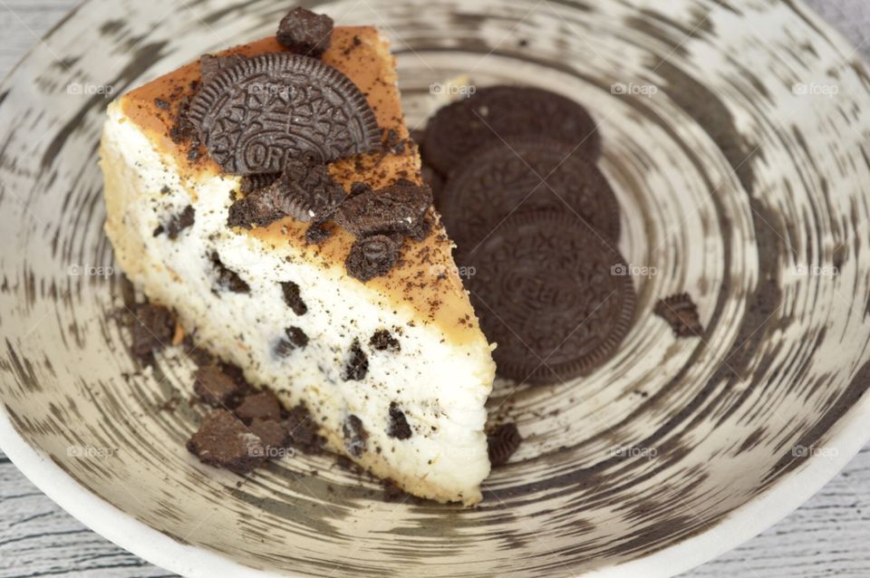 Oreo cookie cheesecake on a contrasting play and Oreo cookies beside the cheesecake