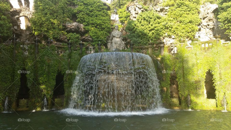 The oval fountain cascades from its basin into a pool set against a rustic monument to nymphs. Villa d'Este, Tivoli