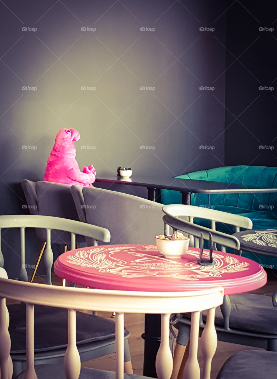 Homunculus Loxodontus sitting at a table with a cup of freshly brewed coffee and a cake. French pastry shop cafe in the center of Moscow