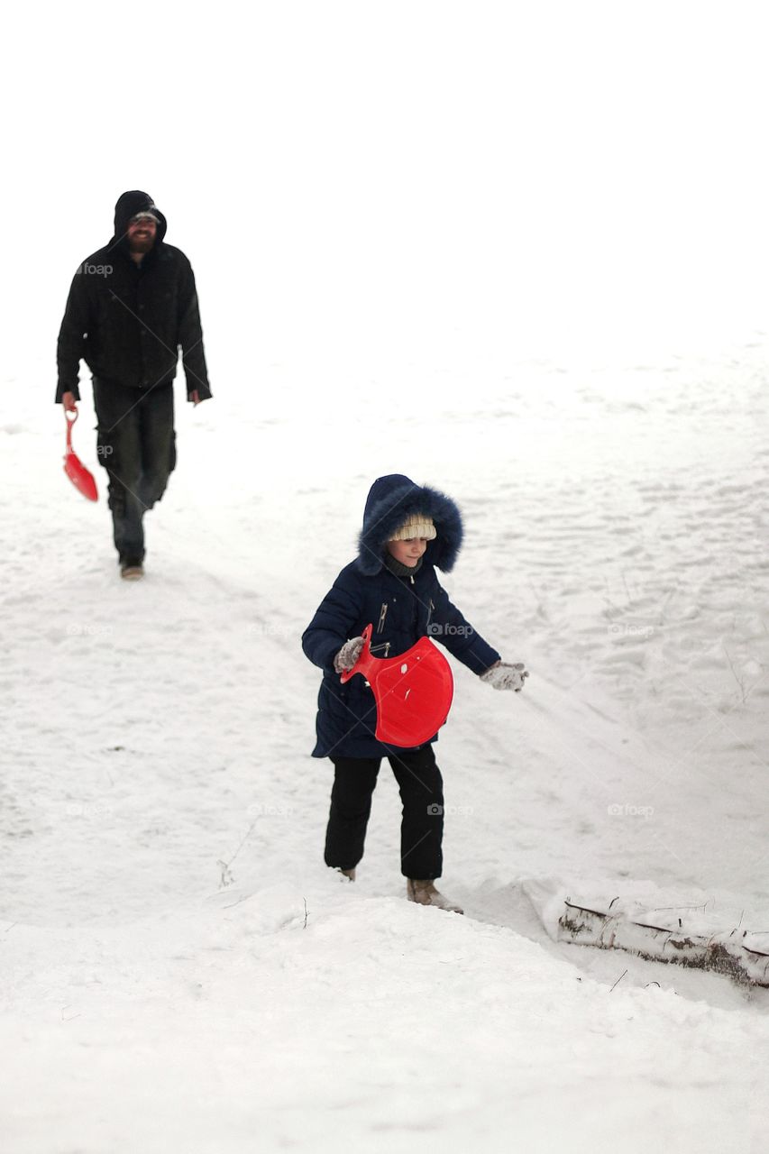 Dad and daughter climb the hill to ride on the ice