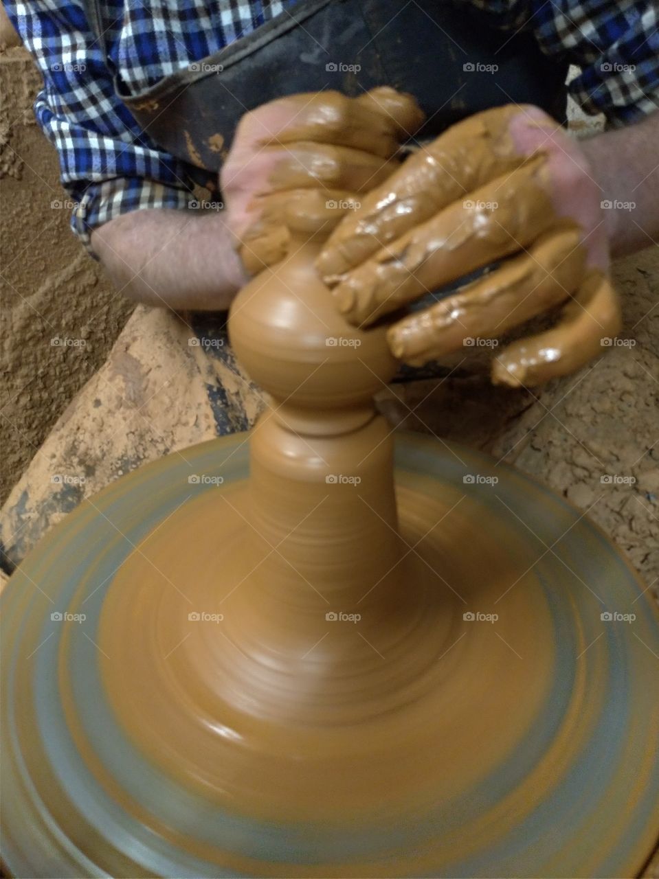 Manos de hombre artesano hacuebdo un objeto de barro
