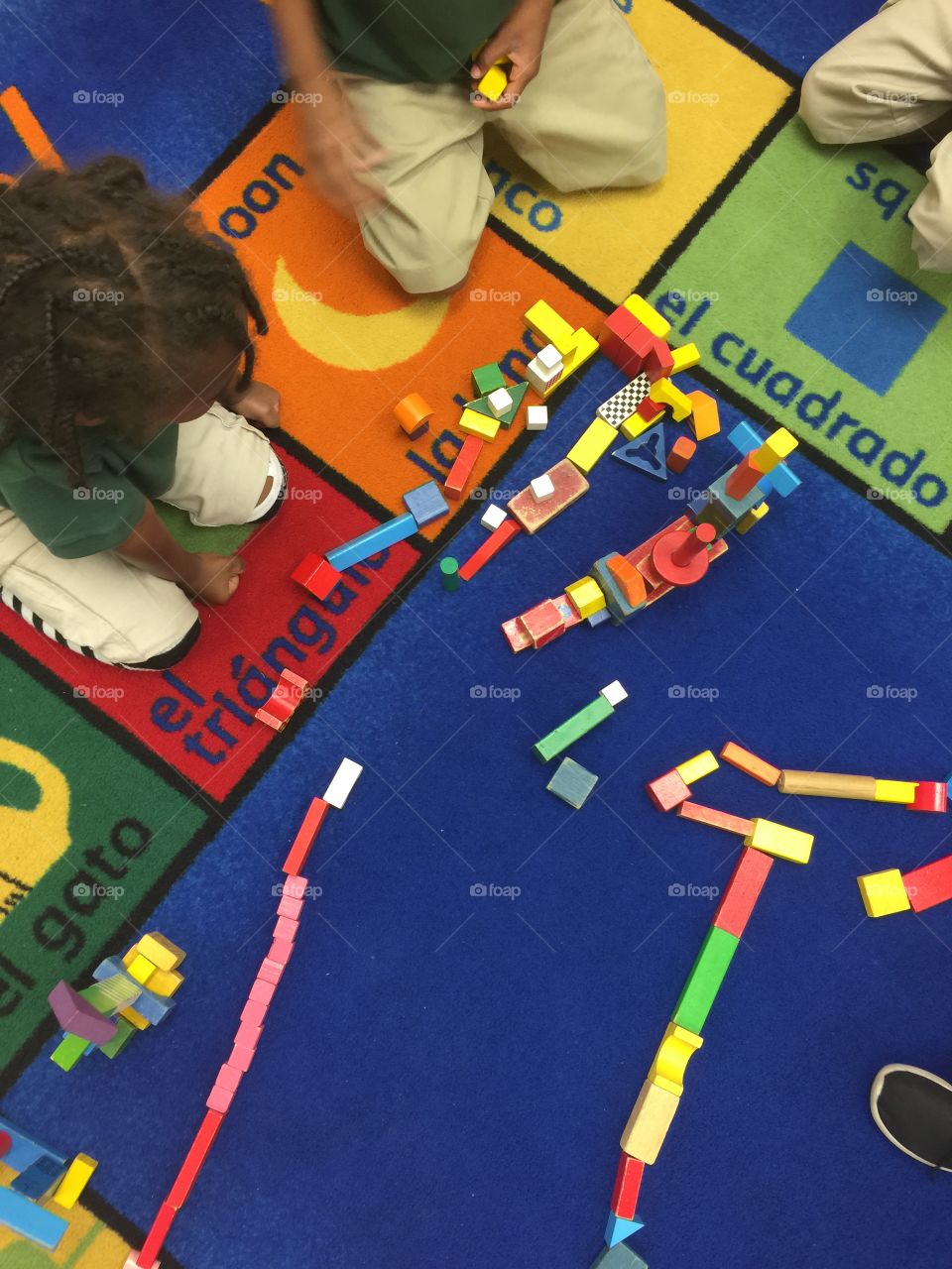 School . Children playing and learning Spanish words on rug in classroom 