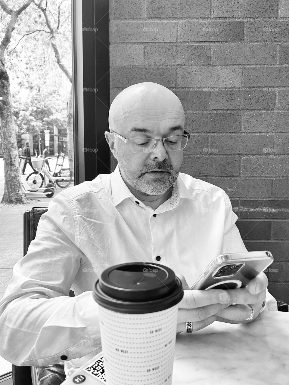 Bold man with beard reading his phone in cafe