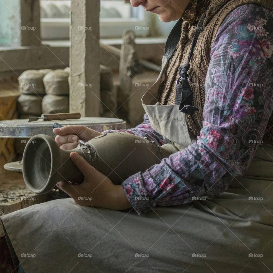 Woman artist works with clay to create a vase.