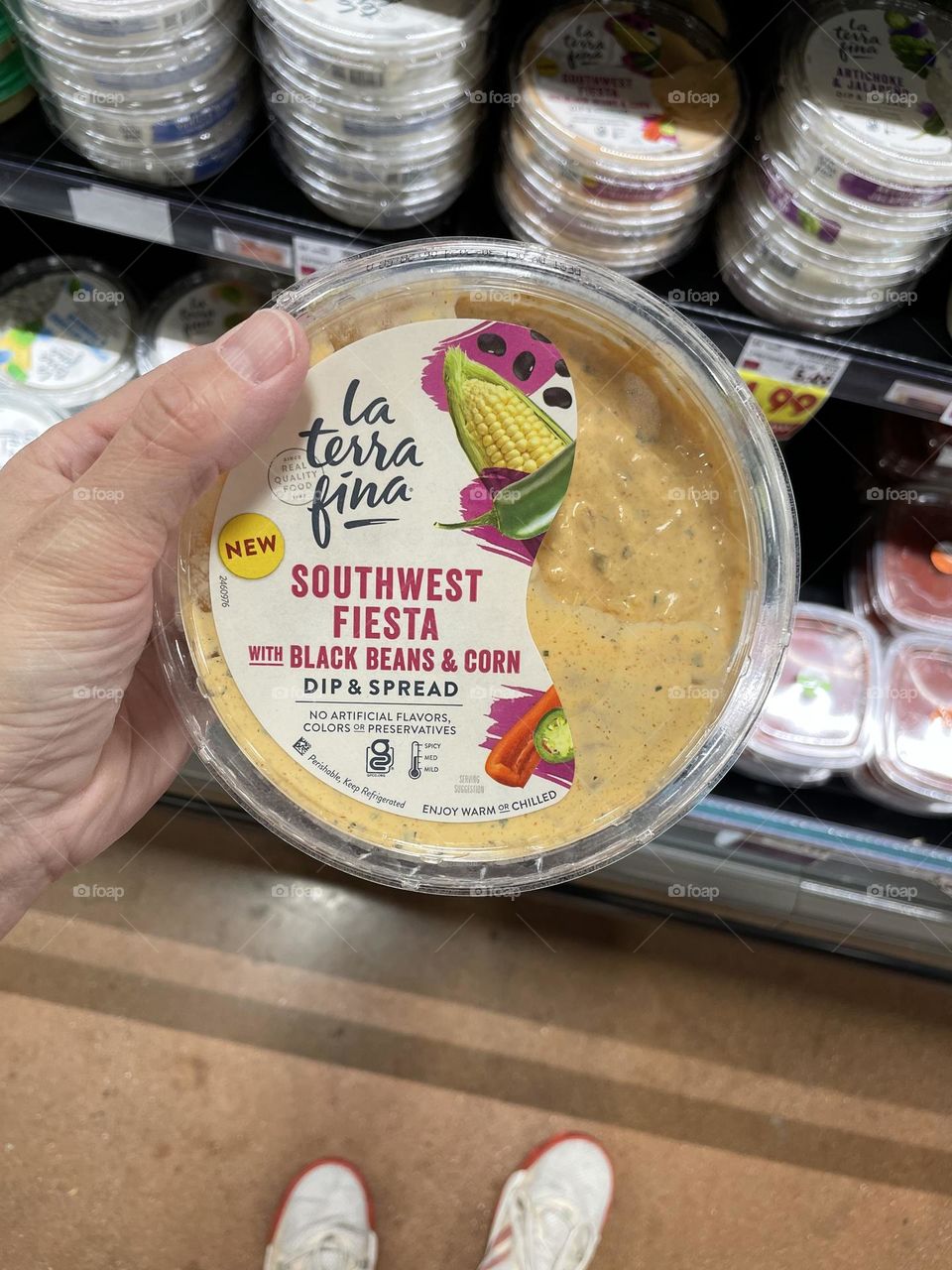 Woman’s hand holding spicy dip, shopping at the grocery store for chip dip, southwest fiesta black bean dip for chips, Mexican themed dip for chips