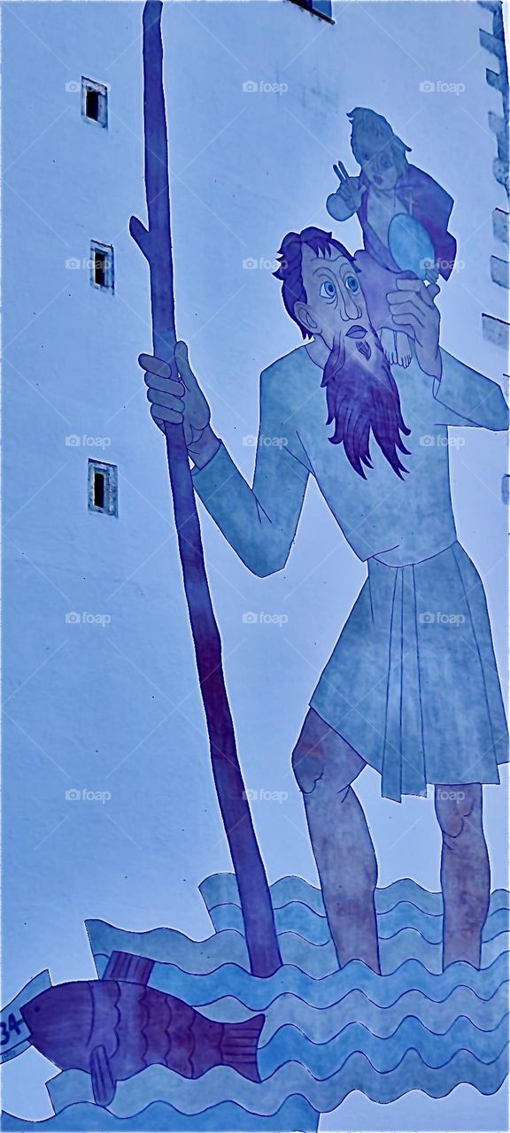 This mural is of the giant „Christopherus“ helping the infant „Jesus““ cross a river carrying him on his shoulder. It adorns the „Herzogsschloß“, the medieval castle of the dukes of the township of „Straubing“ in „Bavaria“. 2023. Hypnotic Productions