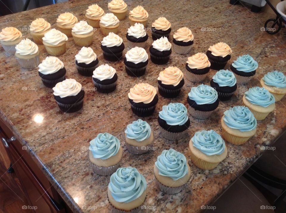 A bunch of cupcakes getting ready for display at a bridal shower.