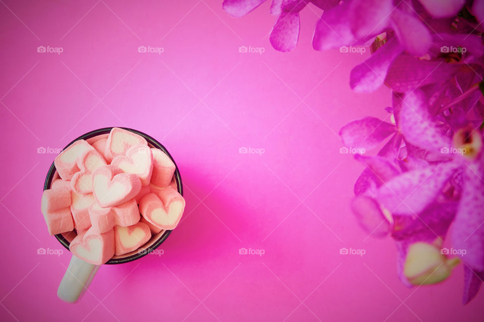 Marshmallows and orchid flower on pink background 