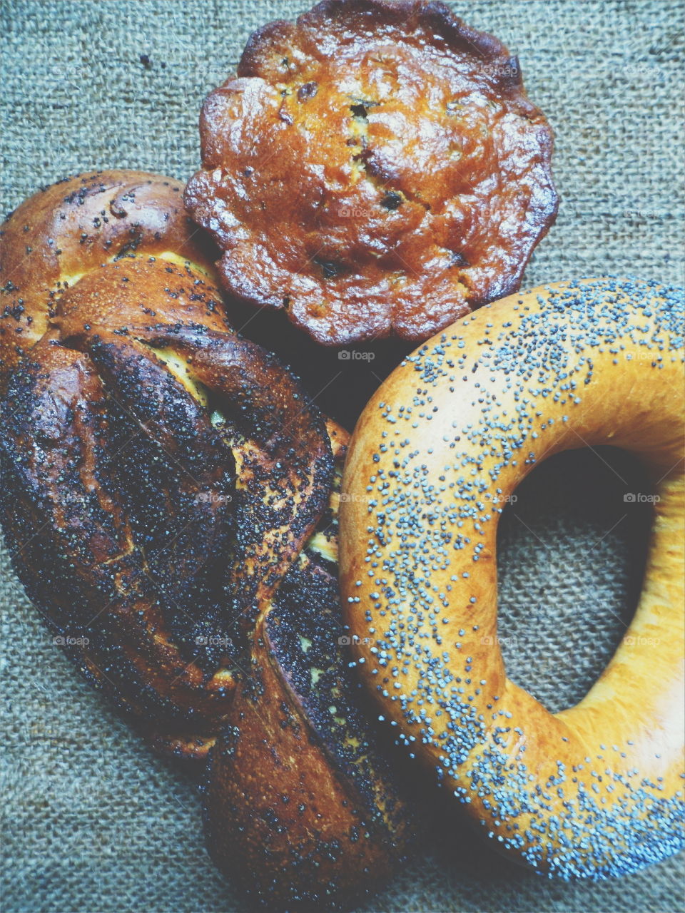 A bagel with poppy seeds and a basket with poppy seeds lie on the table