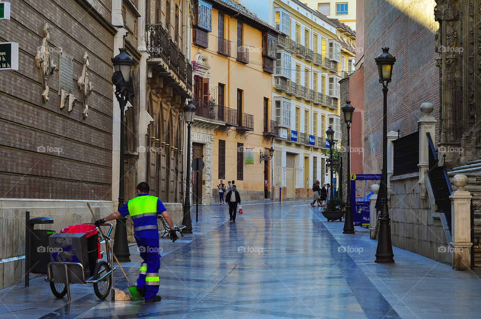 Empty street in Malaga city in the morning and men cleaning. Day before work, 