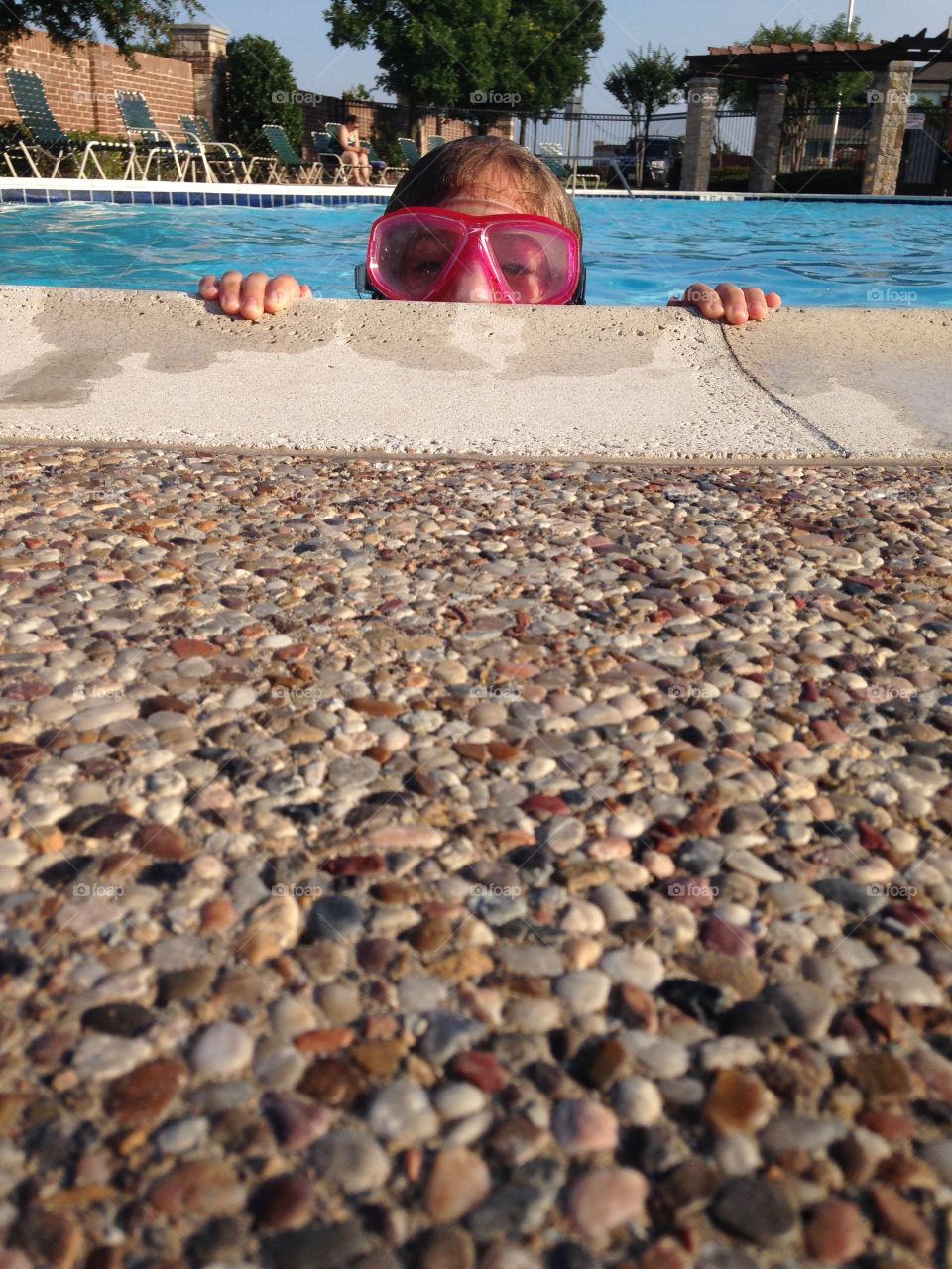 Peek a boo. Girl peeking over the edge of the pool