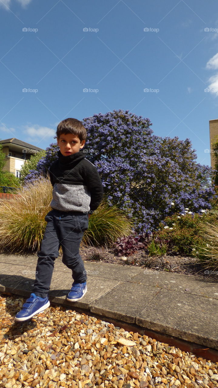 little boy curiously looking crossing the pavement his facial expression is serious