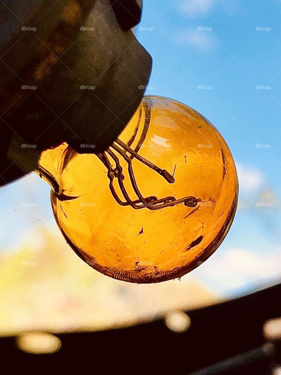 Closeup of amber automotive turn signal light bulb against blue sky 