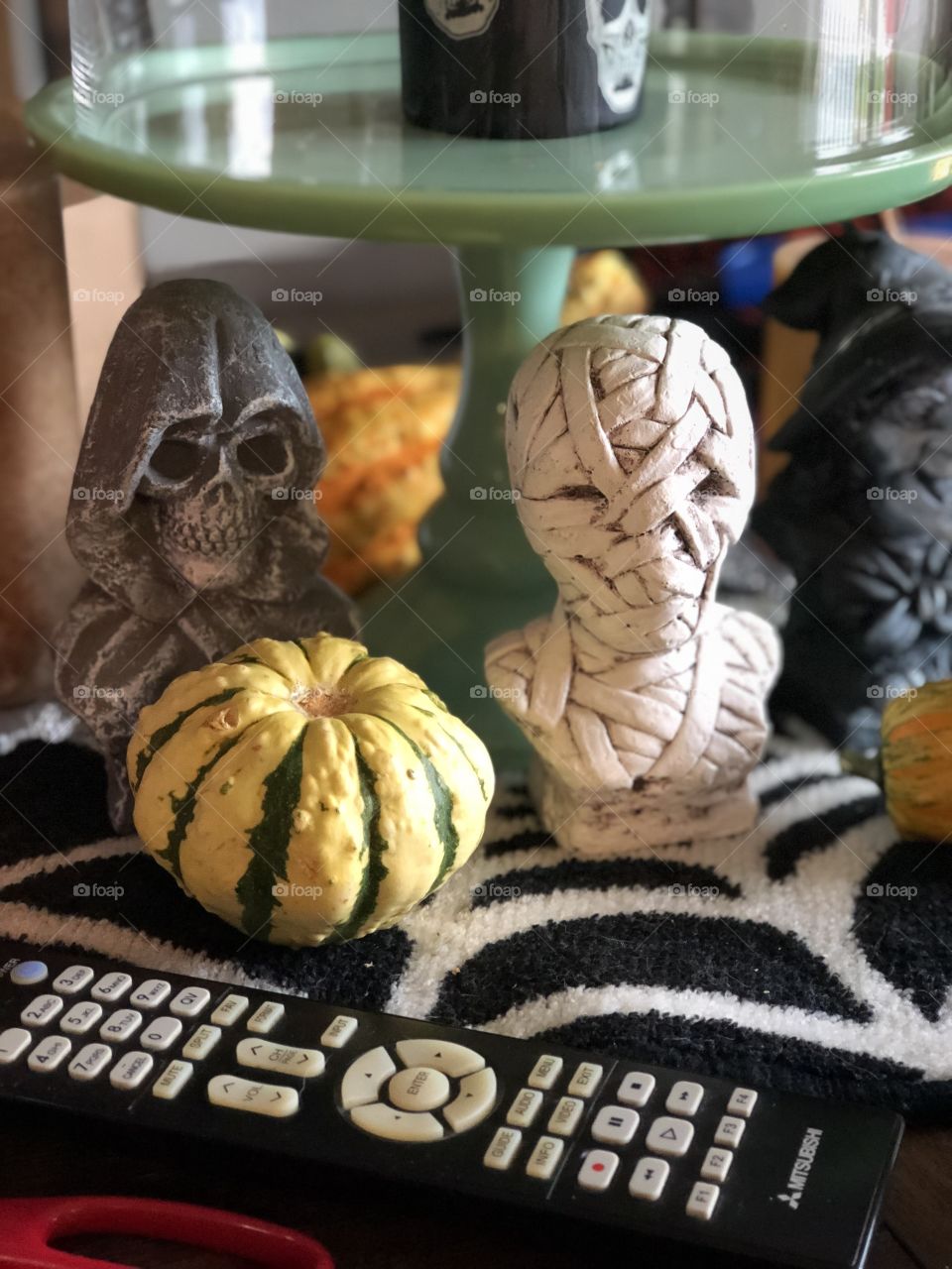 Fall gourds, tv remote, mummy bust, and the bust of a grim reaper
