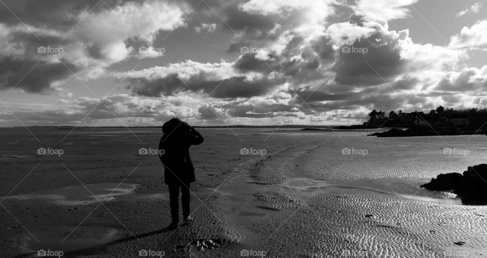 Person standing on wet sandy beach