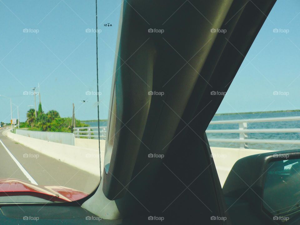 Road trip during the warm summer time in Florida by a bridge sidewalk observing the lagoon from the passenger point of view in the vehicle.