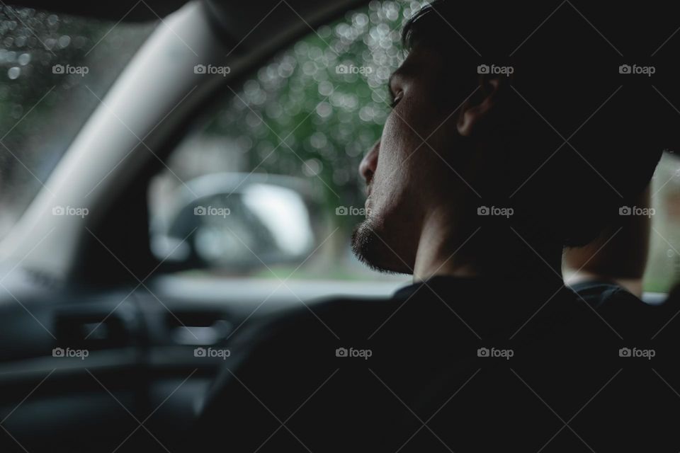 Close-up side view portrait of handsome young caucasian guy sadly sitting inside the car and thinking about something. The concept of sad people, mental health.