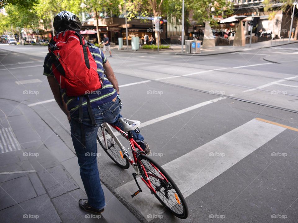 A cyclist waiting for a green light on the street of Melbourne