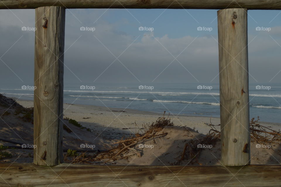 A wooden framed shot of the sand and ocean.