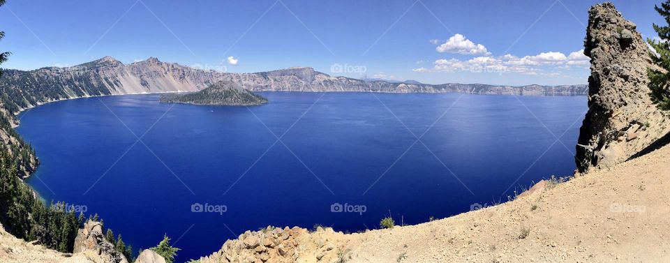 View of deep blue crater lake against blue sky in Oregon