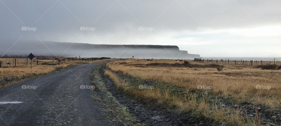 mist covering some cliffs, Brown grass and cloudy sky