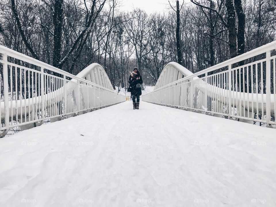 Woman standing on bridge covered with snow