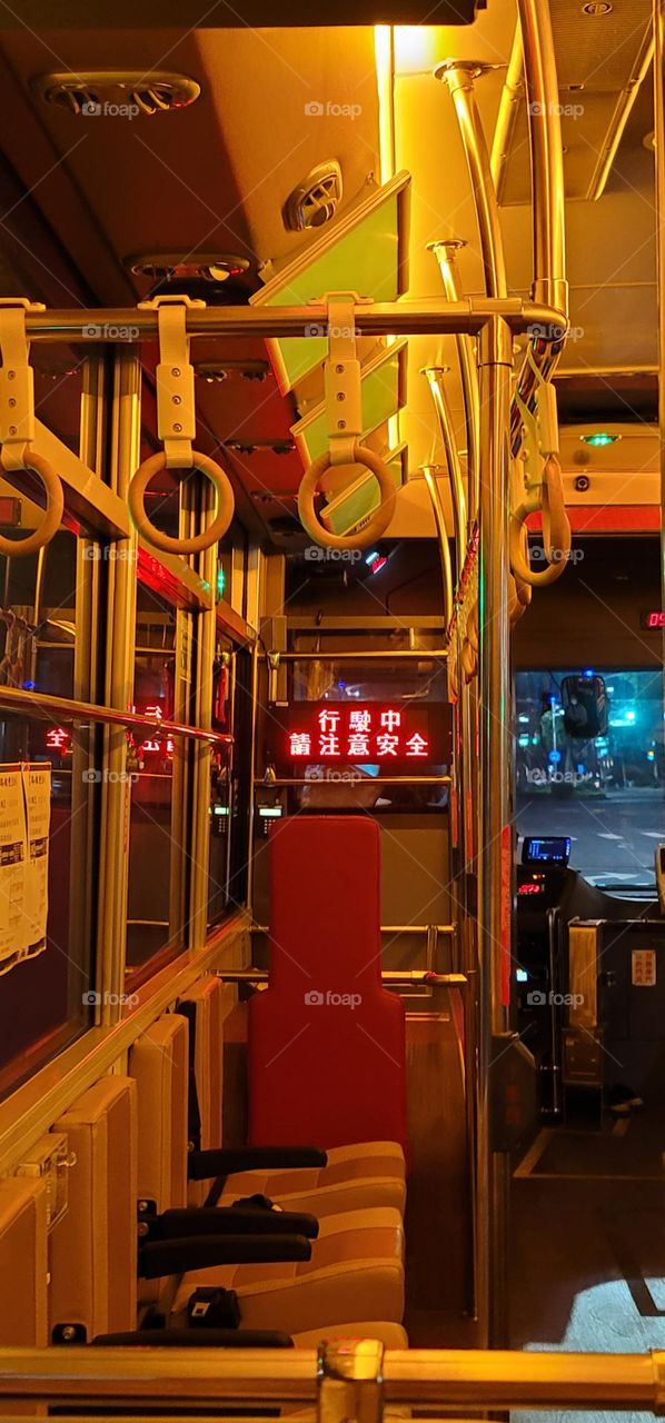 A retro-style bus with a warm yellow light interior. The marquee reads "Please pay attention to safety while driving" in Chinese