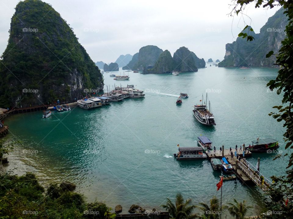 On the dock there were many people and ships anchored, in the distance ships were coming, in the blue water, there were many undulating mountains. The sky was cloudy and not sunny, I was visiting a cave