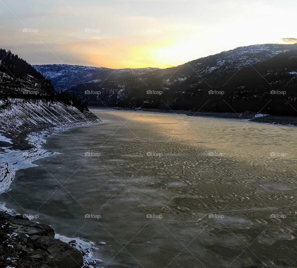 partially frozen water with sunset and mountains