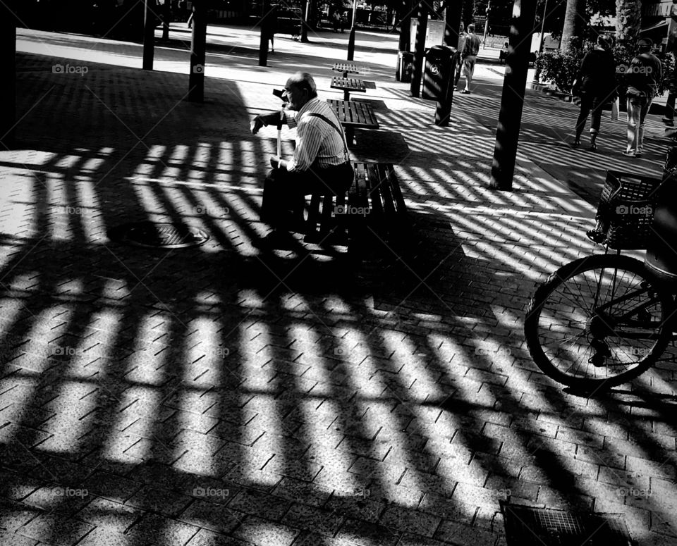 elderly man sitting on a bench in the square