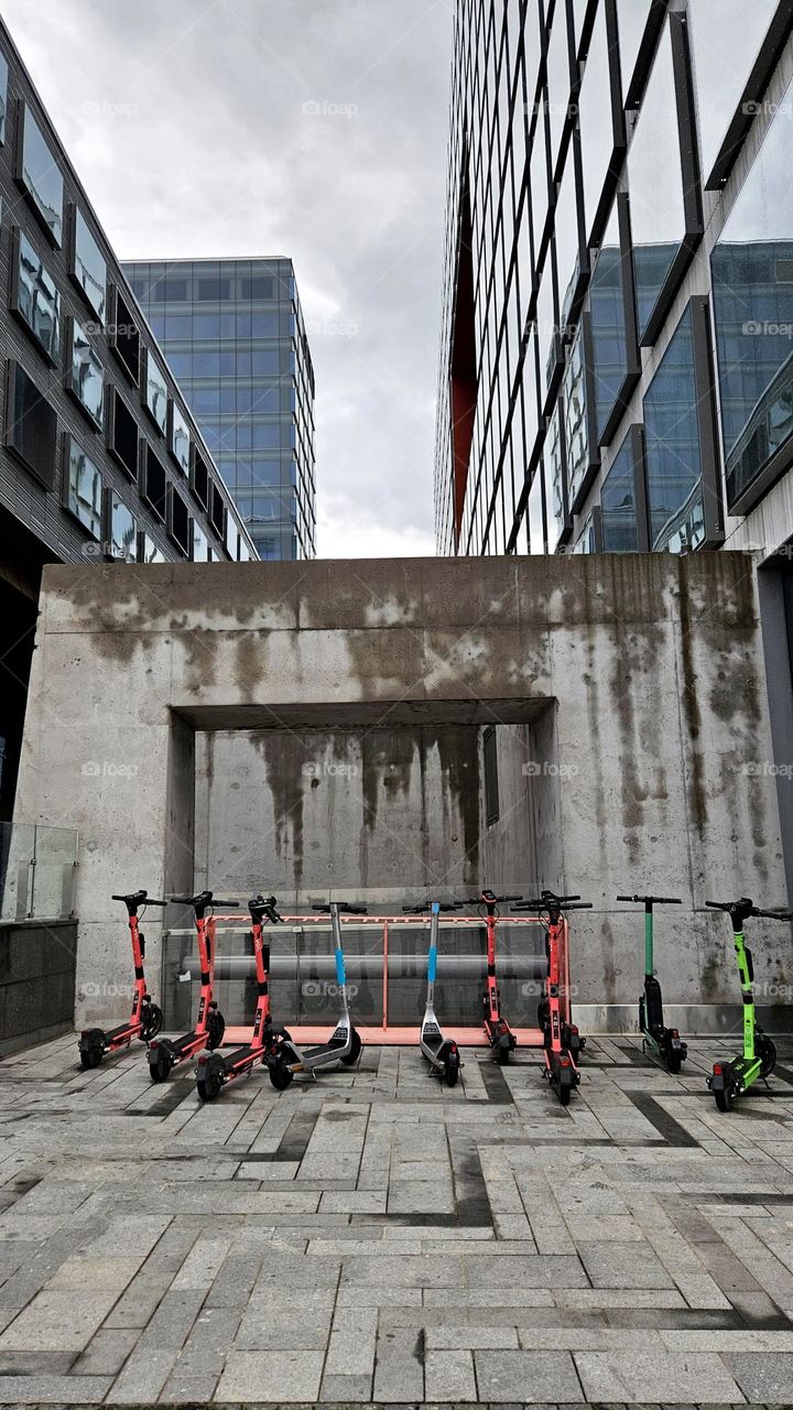 A gray rainy summer day in Finland in Helsinki's Pasila and the newly completed new shopping center Tripla's architecture in the picture. The city's scooters, which can be rented for use, add color to the picture