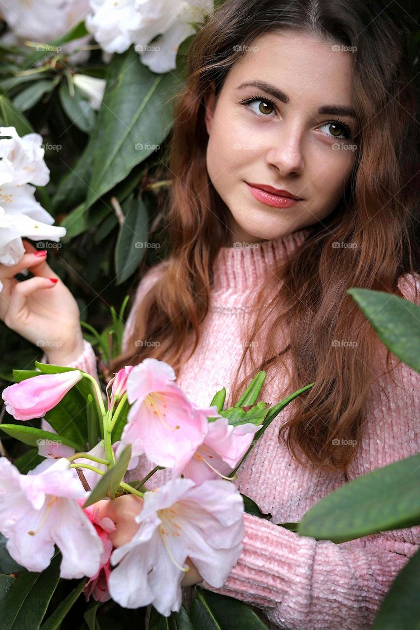 Love pink color. Natural beauty. Young women with long hair in pink outfit. Bushes with pink flowers.