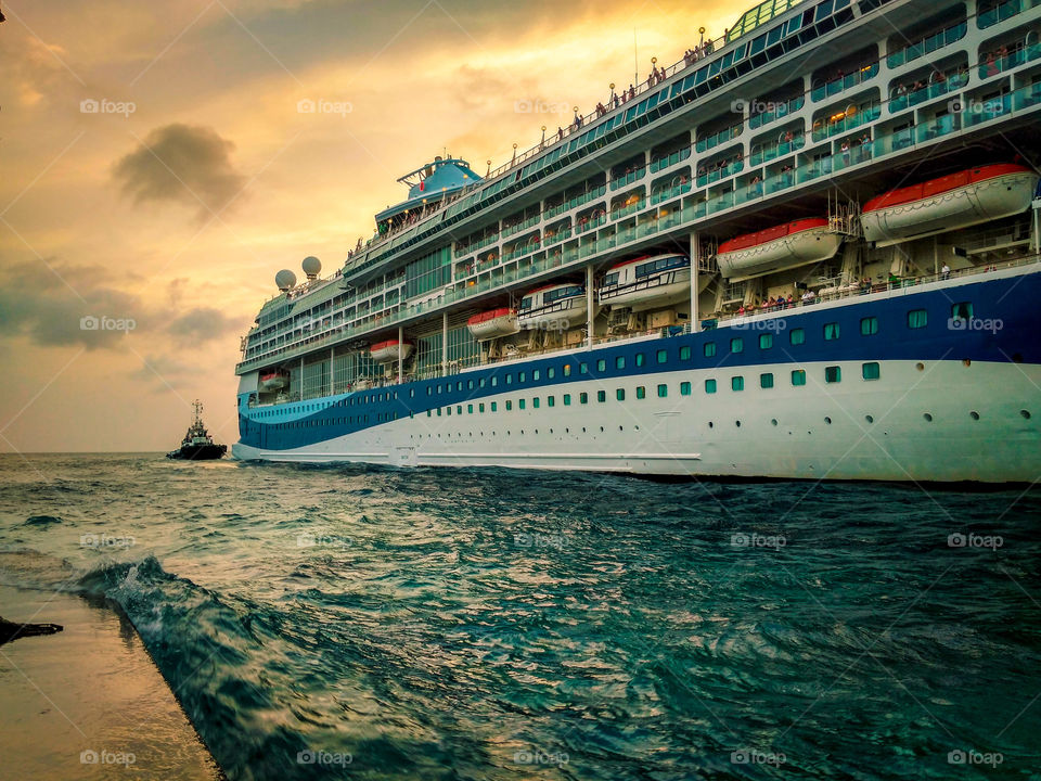 cruise ship guided by a small tow boat through the harbor