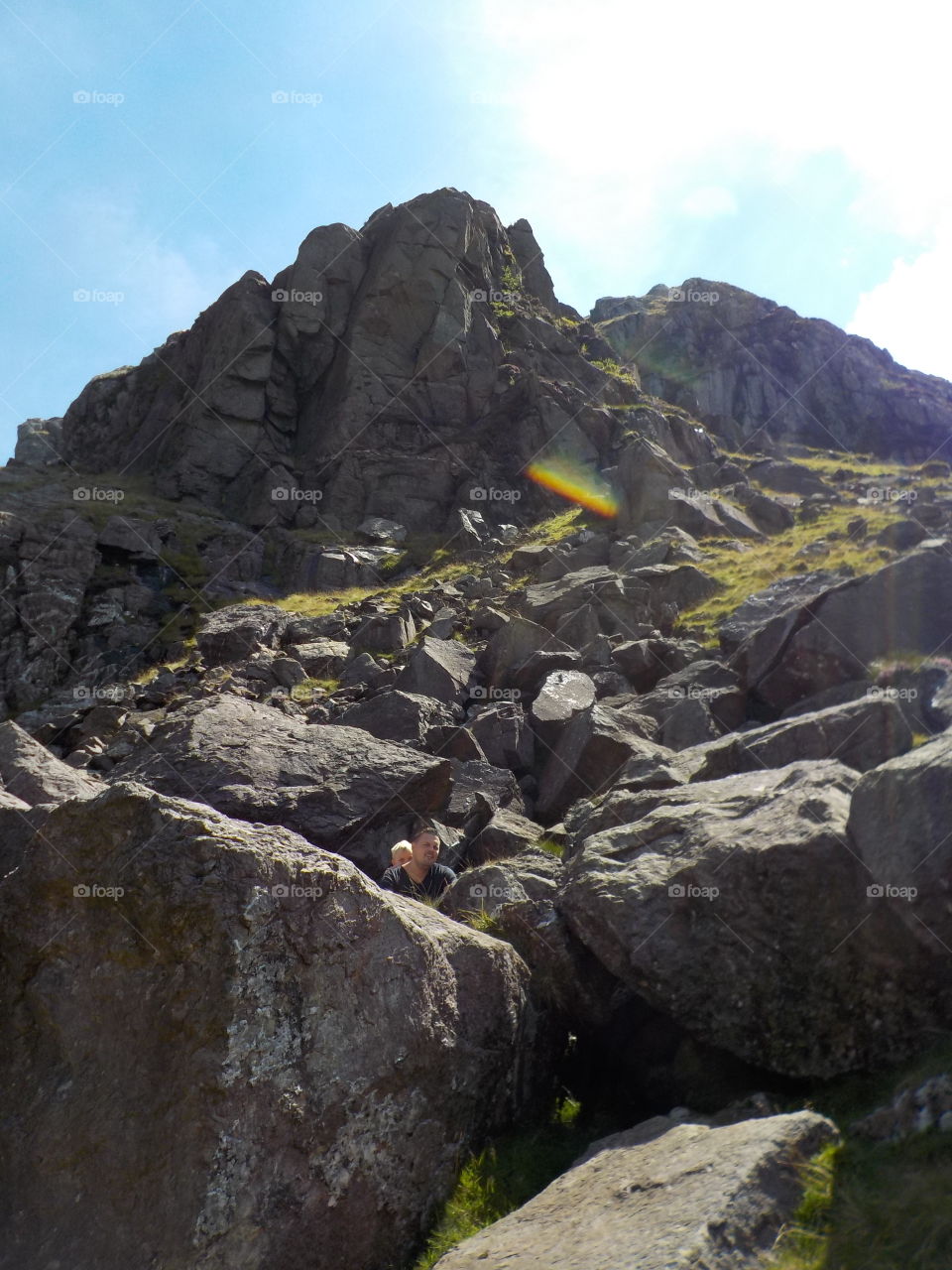 Father and son sitting on rock mountain