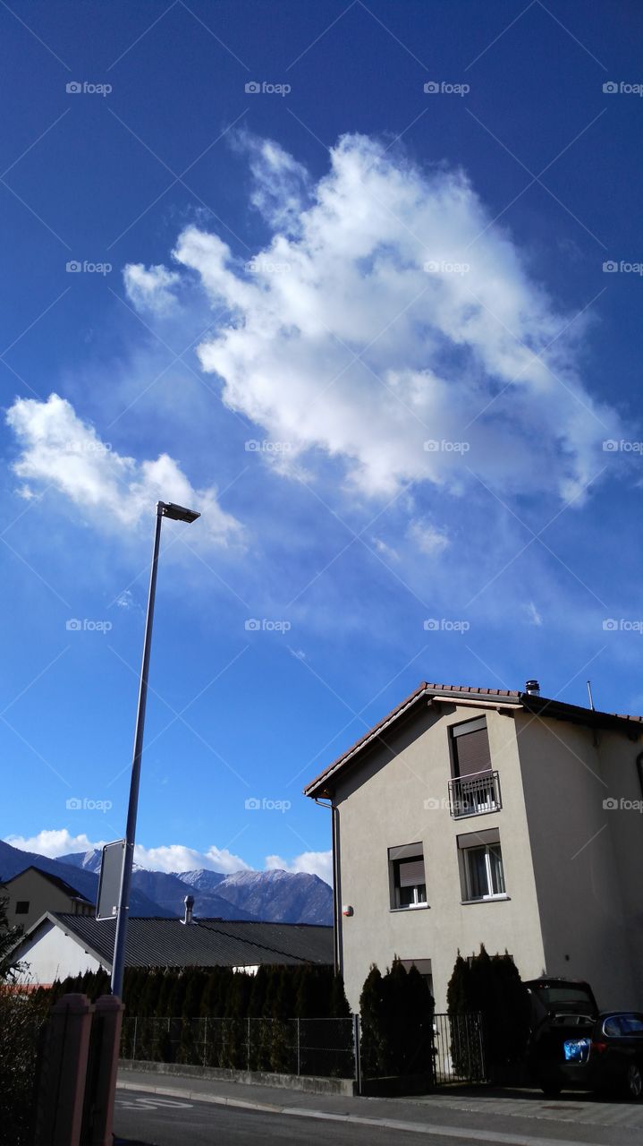 blue sky with clouds and streetlight and house
