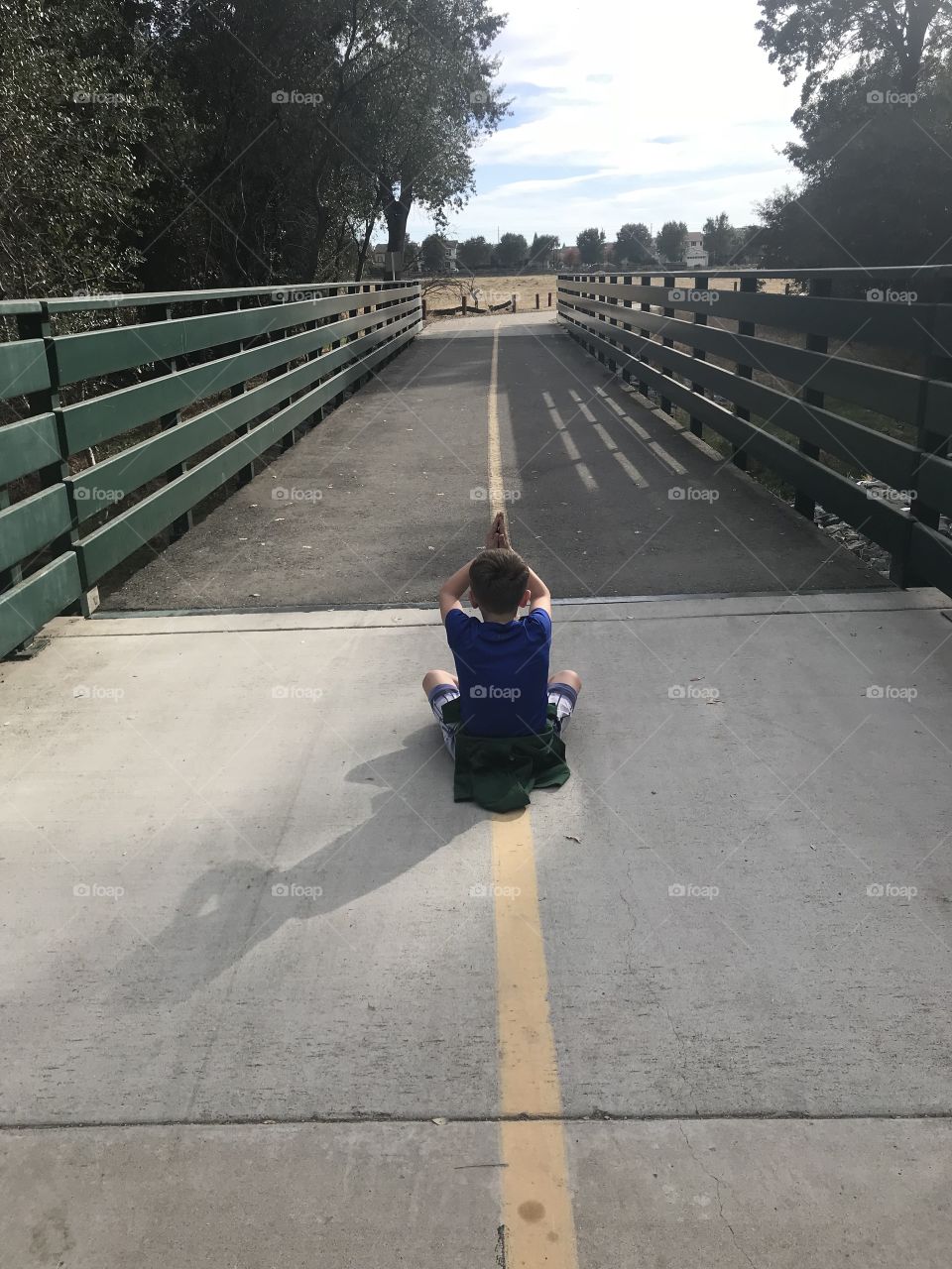 A young boys sitting on the bridge outside in nature meditating peacefully. USA, America