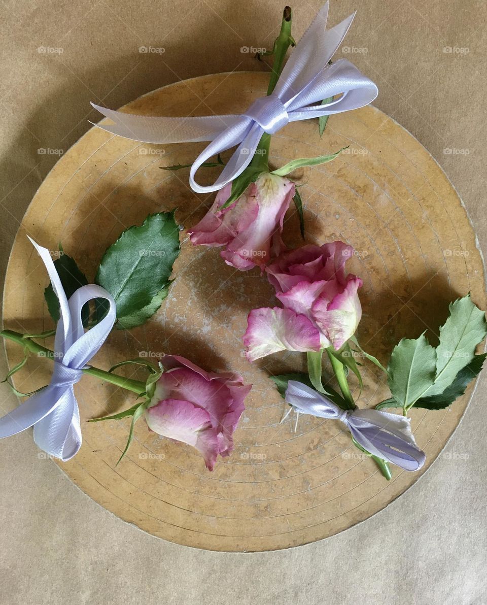 Three roses on a wooden plate