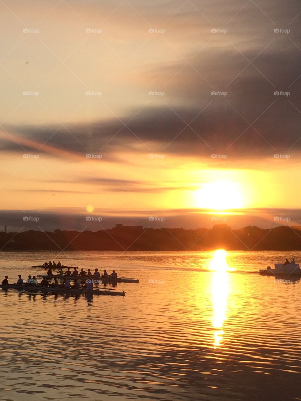 People rowing on sea during sunset